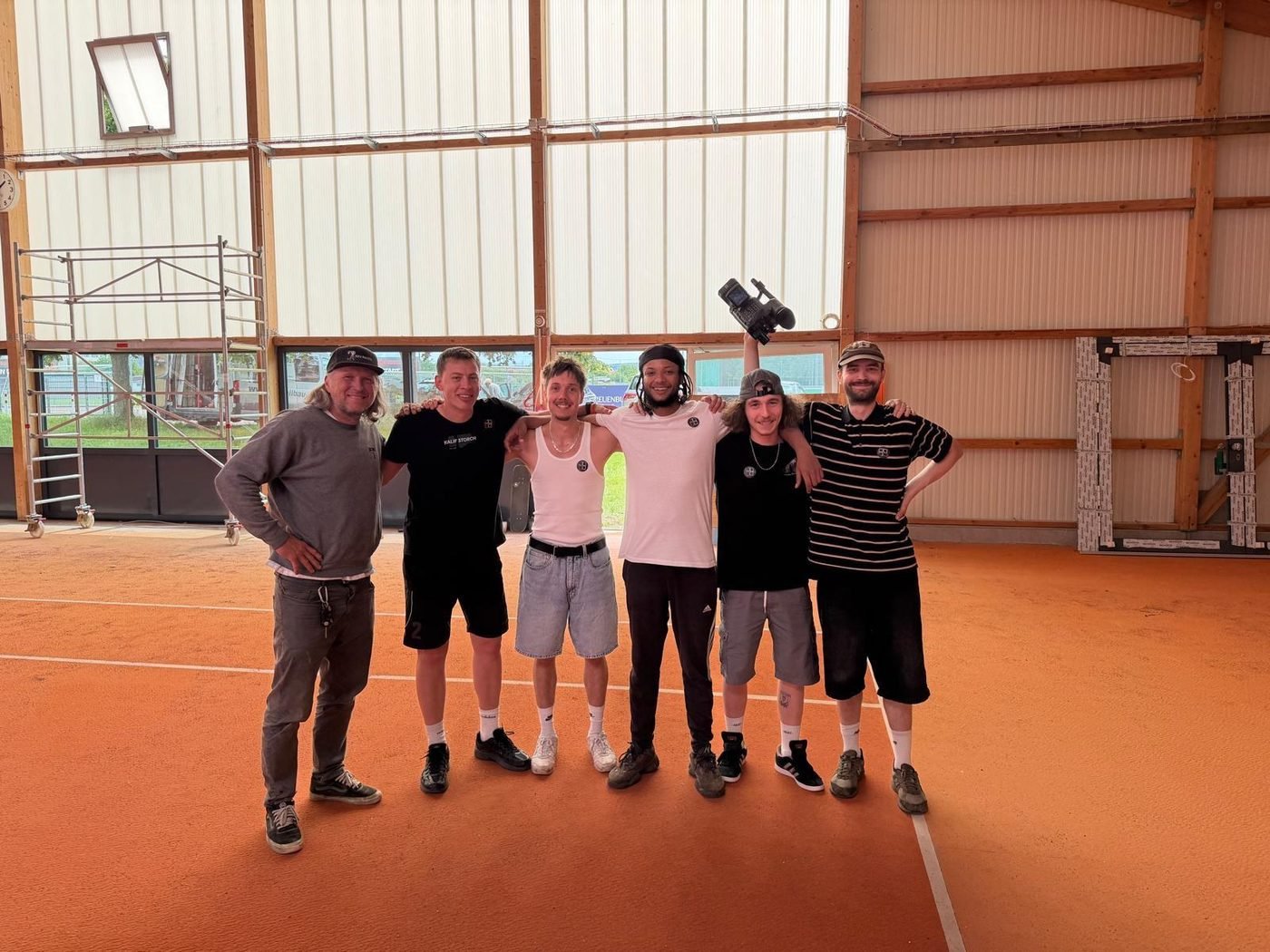 Sechs Leute aus dem Bauteam stehen zusammen auf dem noch orangen Hallenboden